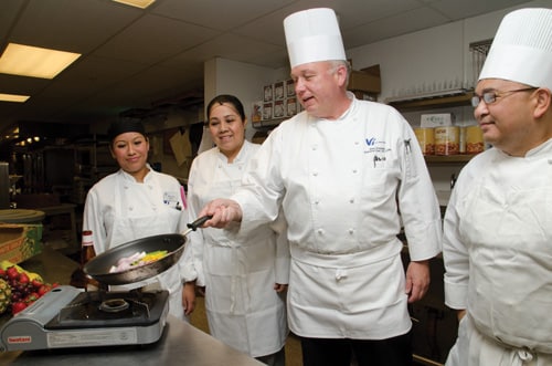 Chef cooking as mentors watch