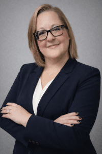 Professional woman with arms crossed in business attire.